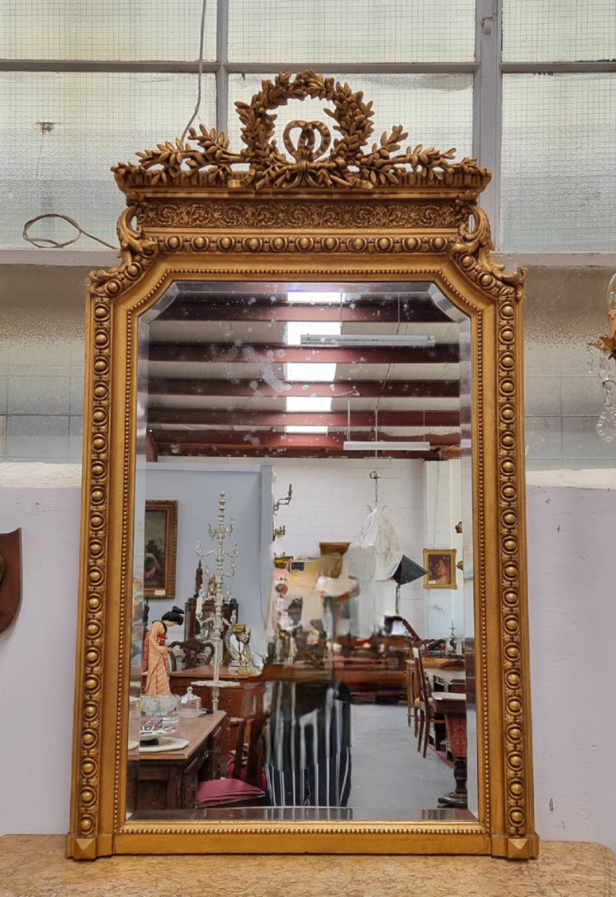 A stunning Napoleon III gilt mantle mirror with its original mirror. The top of the mirror is decorated with a beautiful laurel wreath and detailed decorative carving throughout. It is in good original condition with the bevelled mirror showing natural aging please view photo's.