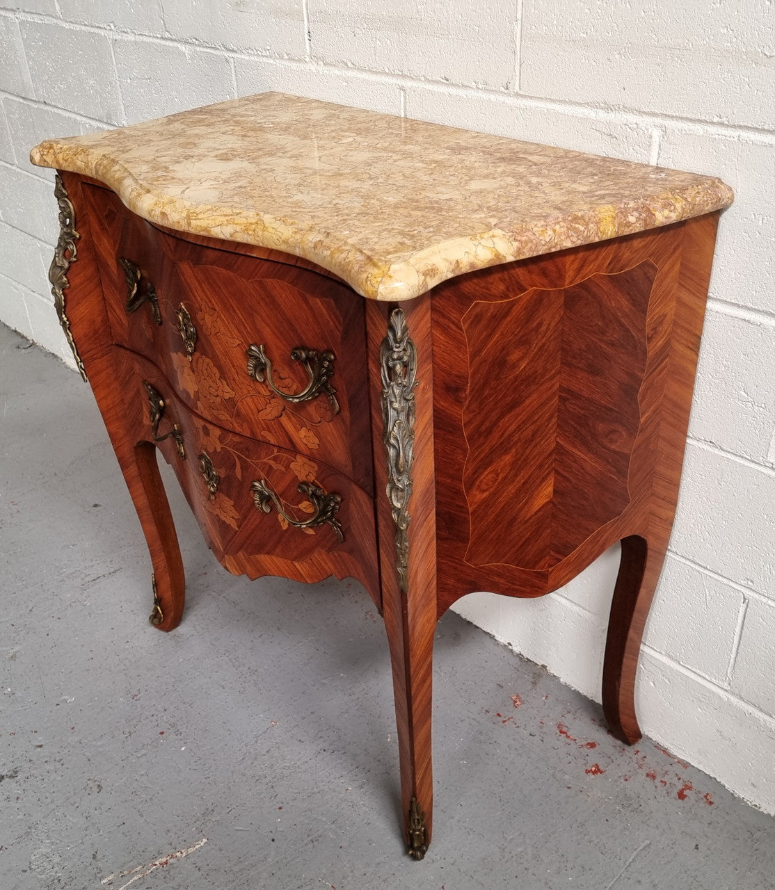 A timeless and compact French Louis XV style two drawer Kingwood marquetry inlaid commode. It features a stunning marble marble top and decorative mounts. The compact design of this commode ensures versatility, making it a perfect addition to any living space, bedroom or hallway. It has been sourced directly from France and is in good original detailed condition.