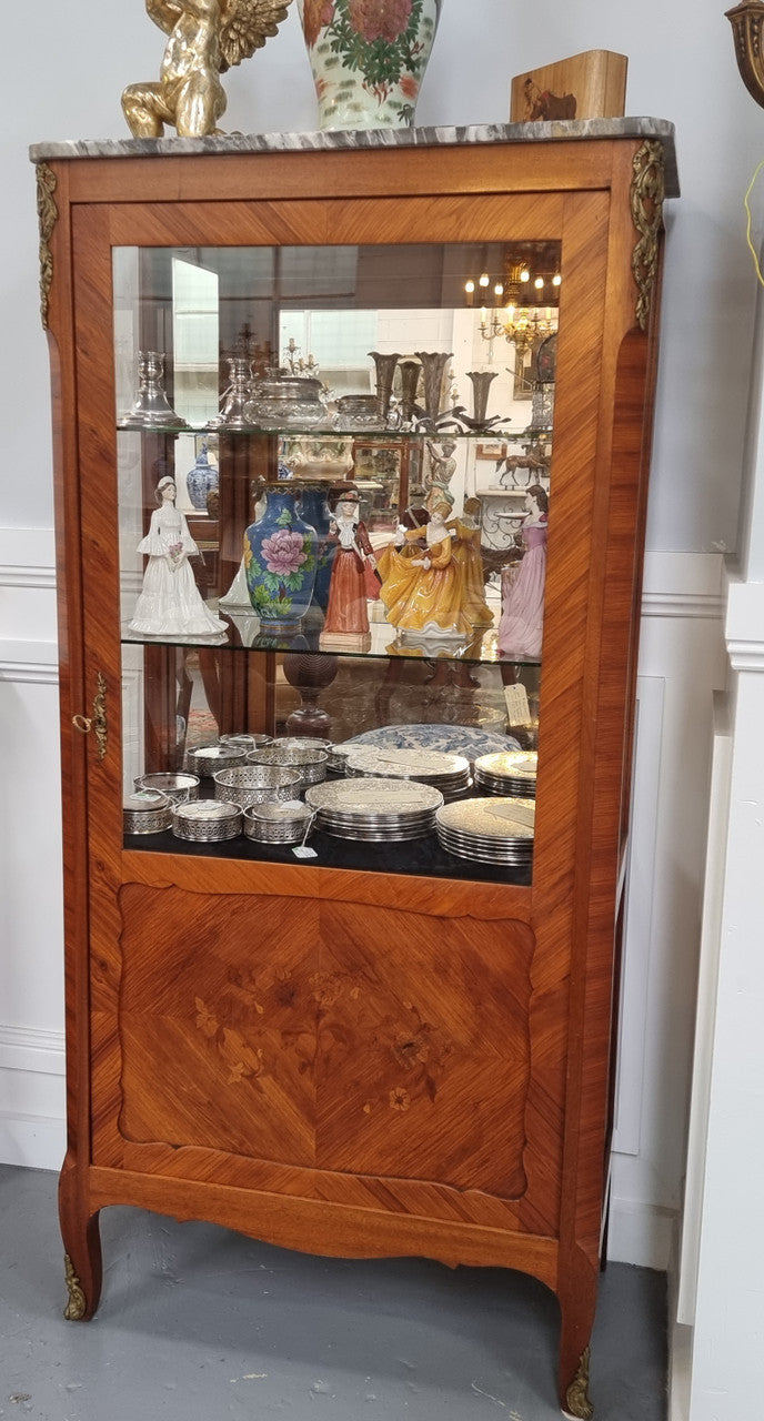 Beautiful French walnut inlaid vitrine with a lovely marquetry design and ormolu mounts. Has a beautiful coloured marble top and two glass shelves. In good original condition.