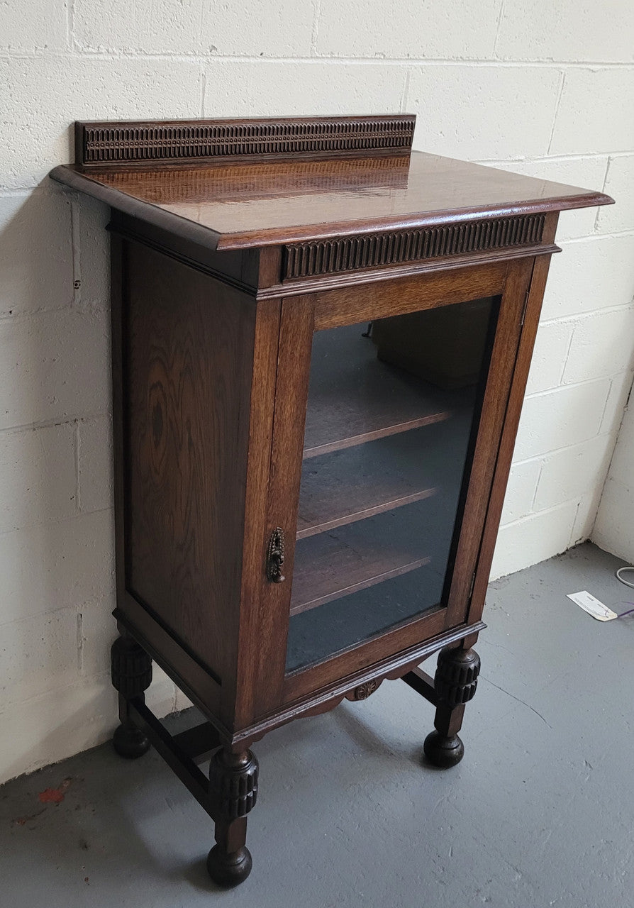 A very practical compact Oak Tudor style display cabinet with three fixed shelves. In good original detailed condition.