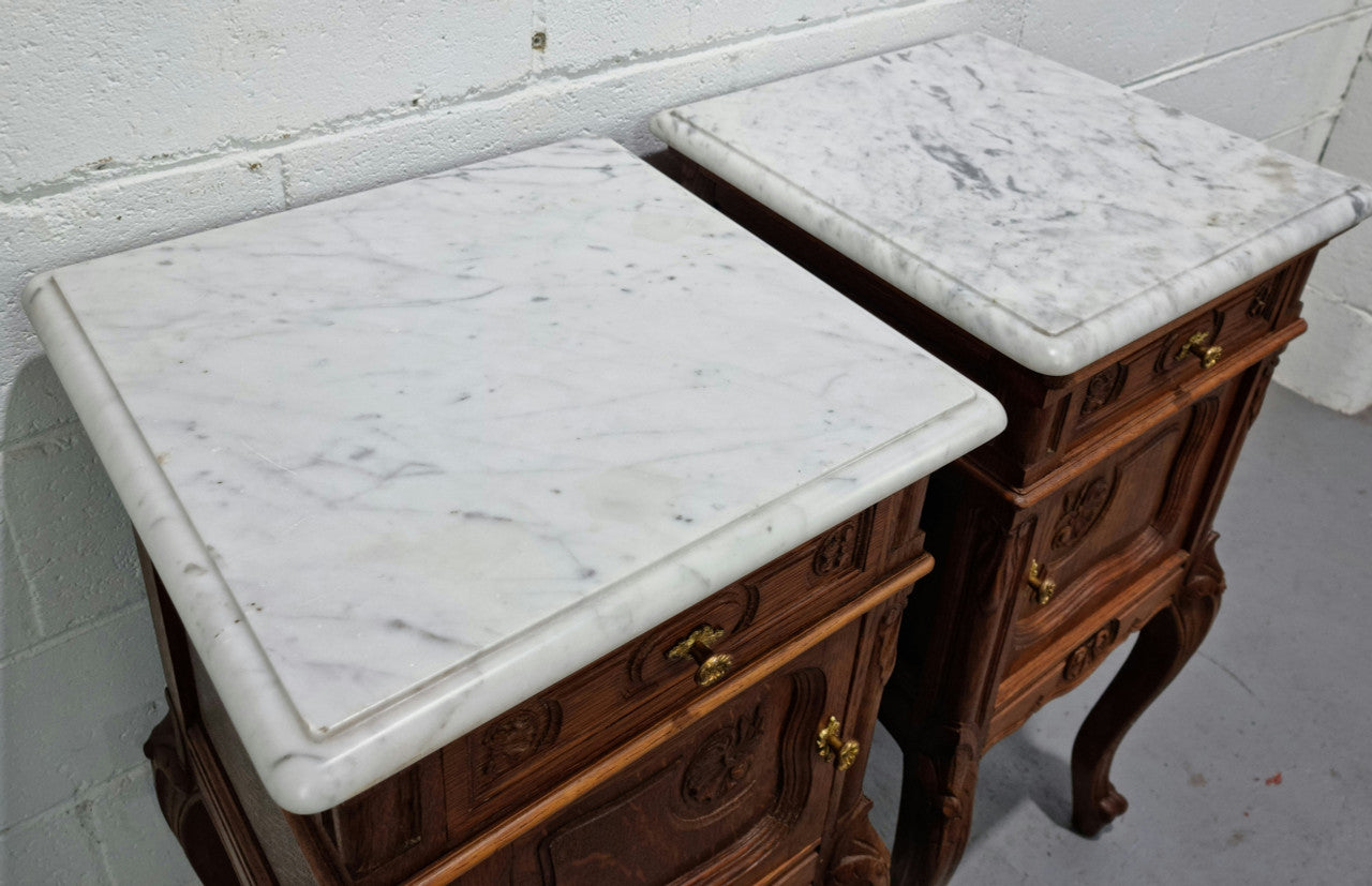 Lovely pair of French Oak carved Louis XV style bedside cabinets with a white marble top, drawer and cupboard in good original detailed condition.
