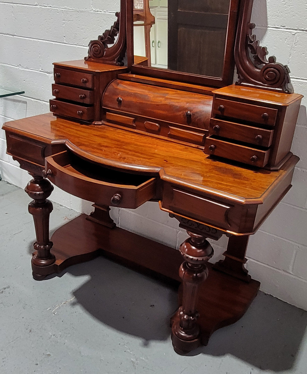 Beautiful Flame Mahogany Victorian duchess dressing table. Circa 1880 in date. It has a serpentine front outline and has an adjustable swing frame mirror. It is fitted with a central roll up storage section and then has three small drawers to either side, aswell as a central drawer in the middle of the serpentine front. It is in good original condition.