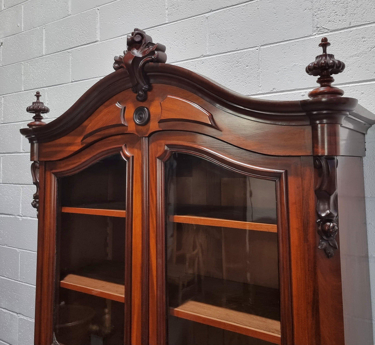 Antique Mahogany two door Biedermeier style bookcase with four fully adjustable shelves and a drawer at the bottom. The two wooden finials at the top are easily removed for a different look of desired. In good original detailed condition.