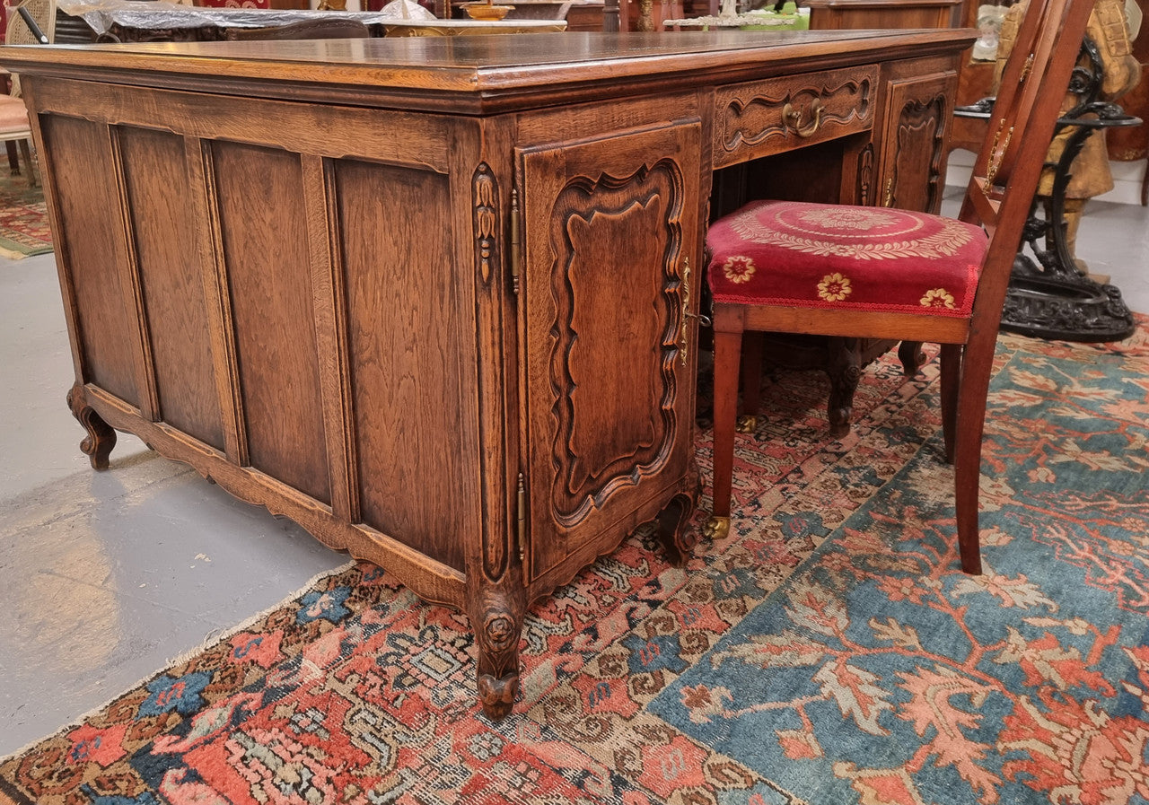 Fabulous Louis XV style French Oak beautifully carved full partners desk with an amazing tooled leather top. Both sides have a functioning drawer in the middle and two cupboards either side. On both sides one cupboard door opens up to four smaller internal drawers. Plenty of storage space and a large top surface to work on. It is in good original detailed condition.