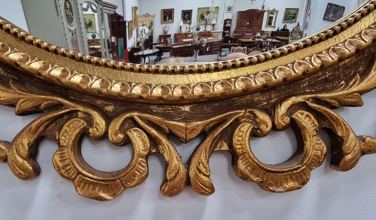 Large round convex mirror in a decorative carved wood gilt frame. In good original detailed condition.