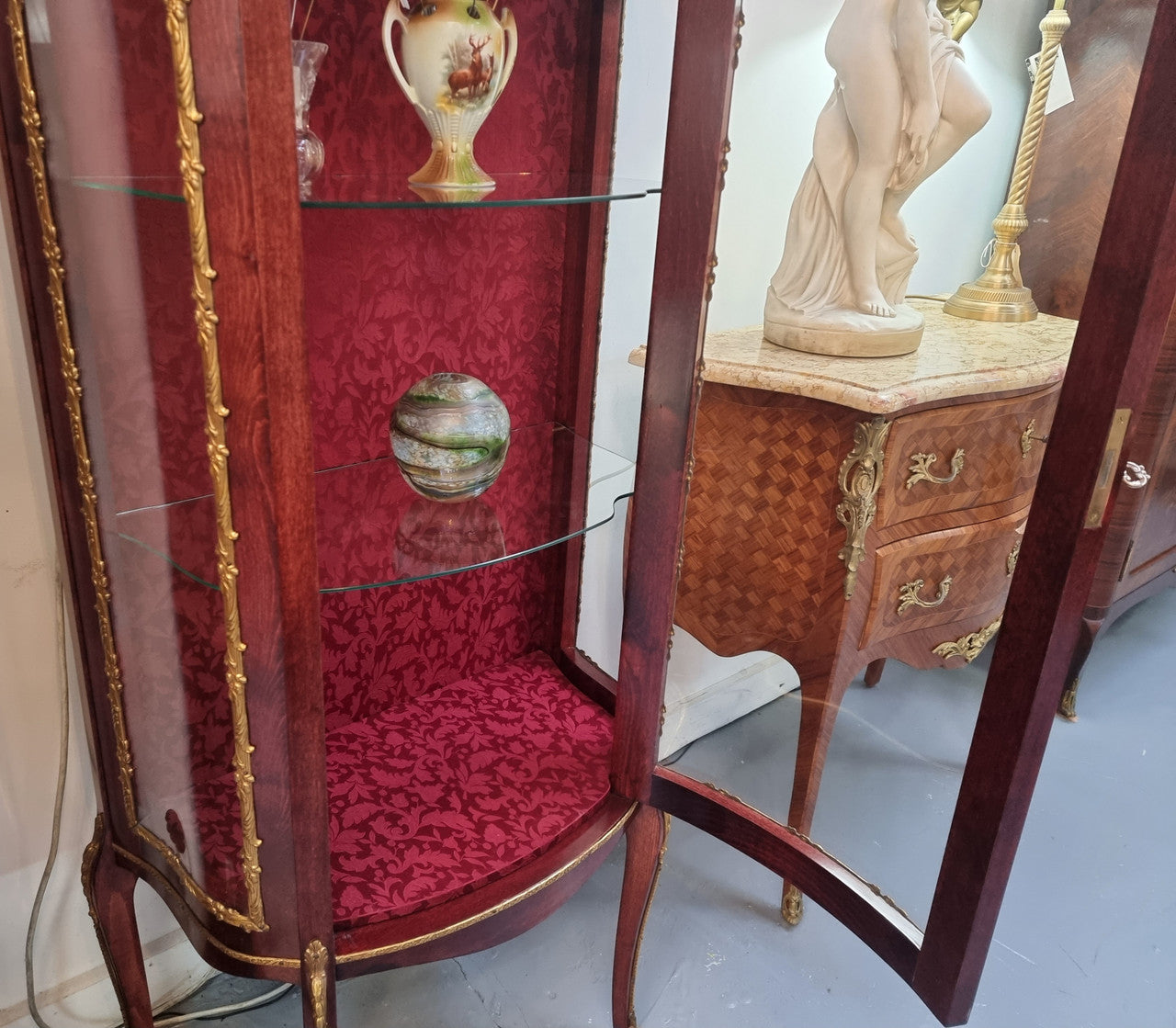 French Mahogany two shelf vitrine with curved glass and brass mounts. It has a lovely frabic interior and two glass shelves. In good original detailed condition.