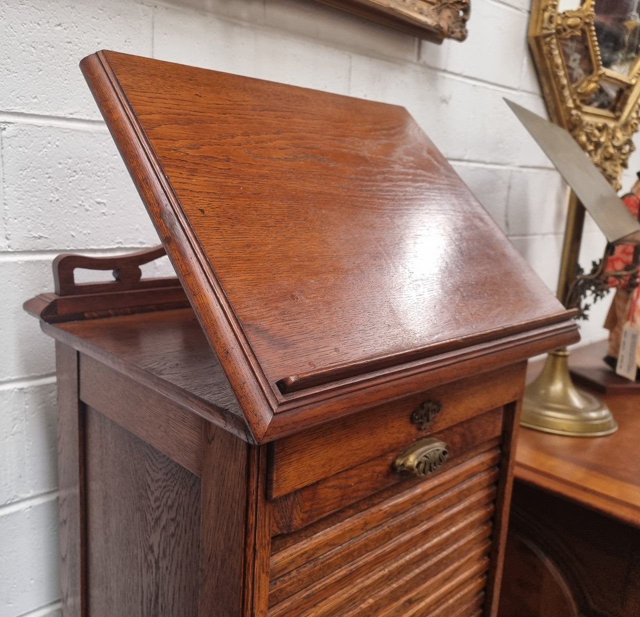 Antique Edwardian roll top Tambour file cabinet desk. This practical antique tambour front filing cabinet dates around 1900 in the Edwardian period and is constructed from Oak. This antique cabinet has an adjustable writing slope, above a tambour front with key and working lock. It has been sourced locally and is in good original detailed condition.