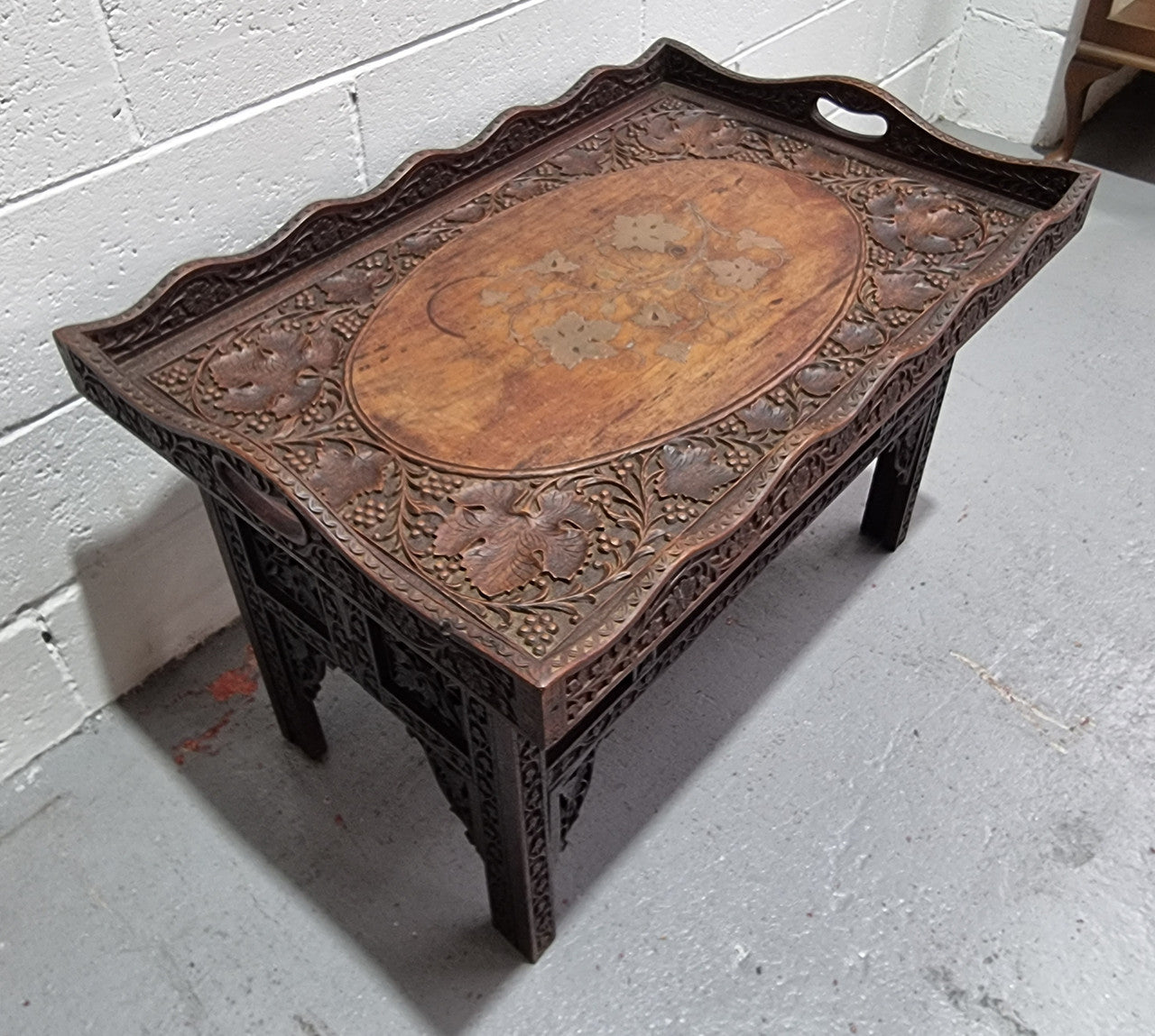 Anglo Indian folding occasional table with lift-up tray top. The tray has brass inlay and ornate carvings. The bottom of the table folds down and it is in good original condition.