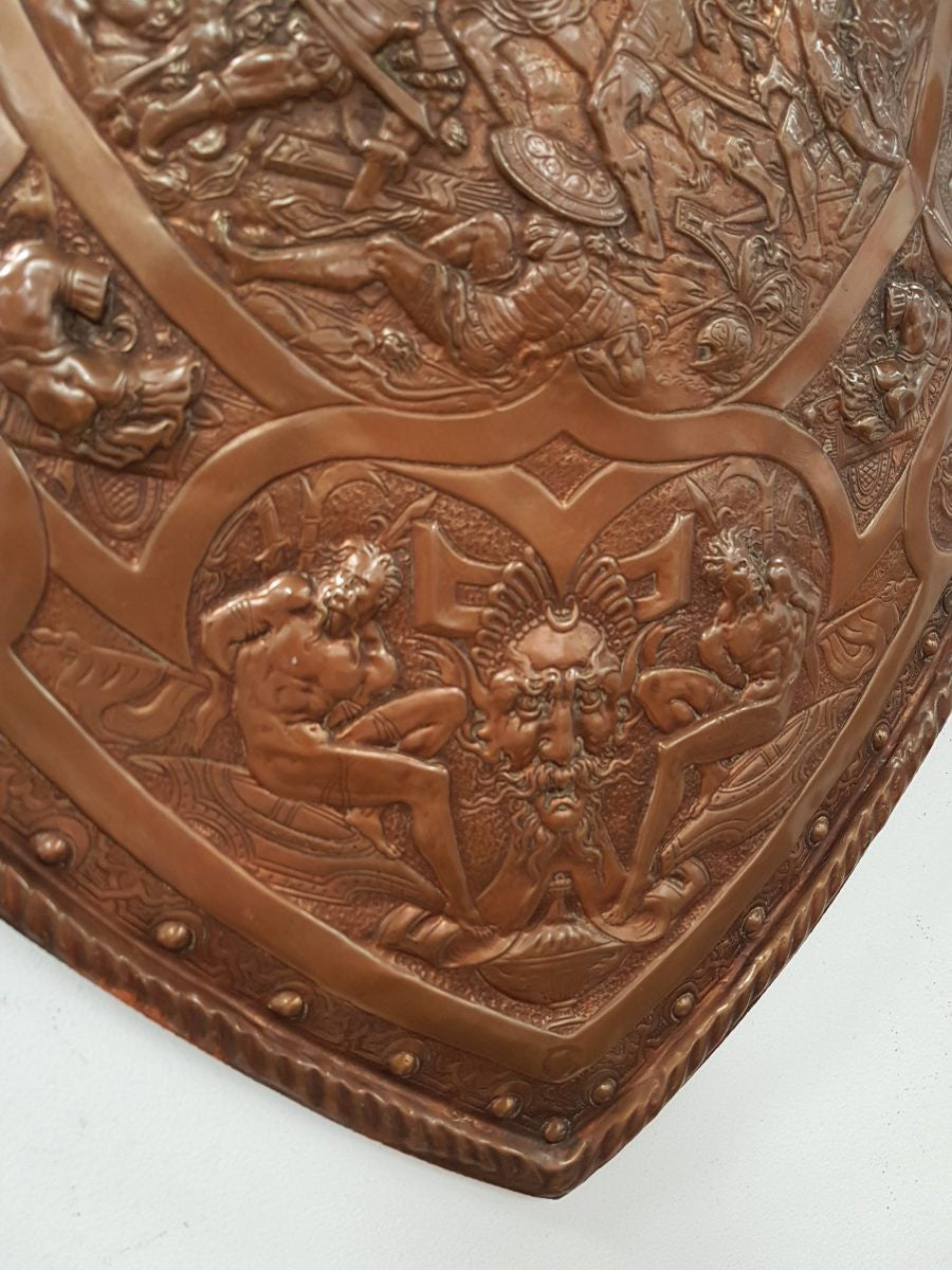 A beautiful European antique repousse copper shield, depicting a battle scene and with metal swords. It has been sourced from France and is in good original condition.