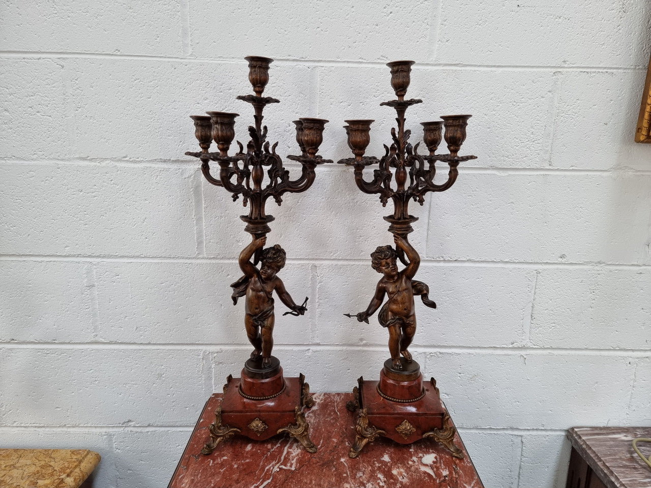 Pair of highly decorative French cherub candelabras with bronzed metal and marble. In good original detailed condition.