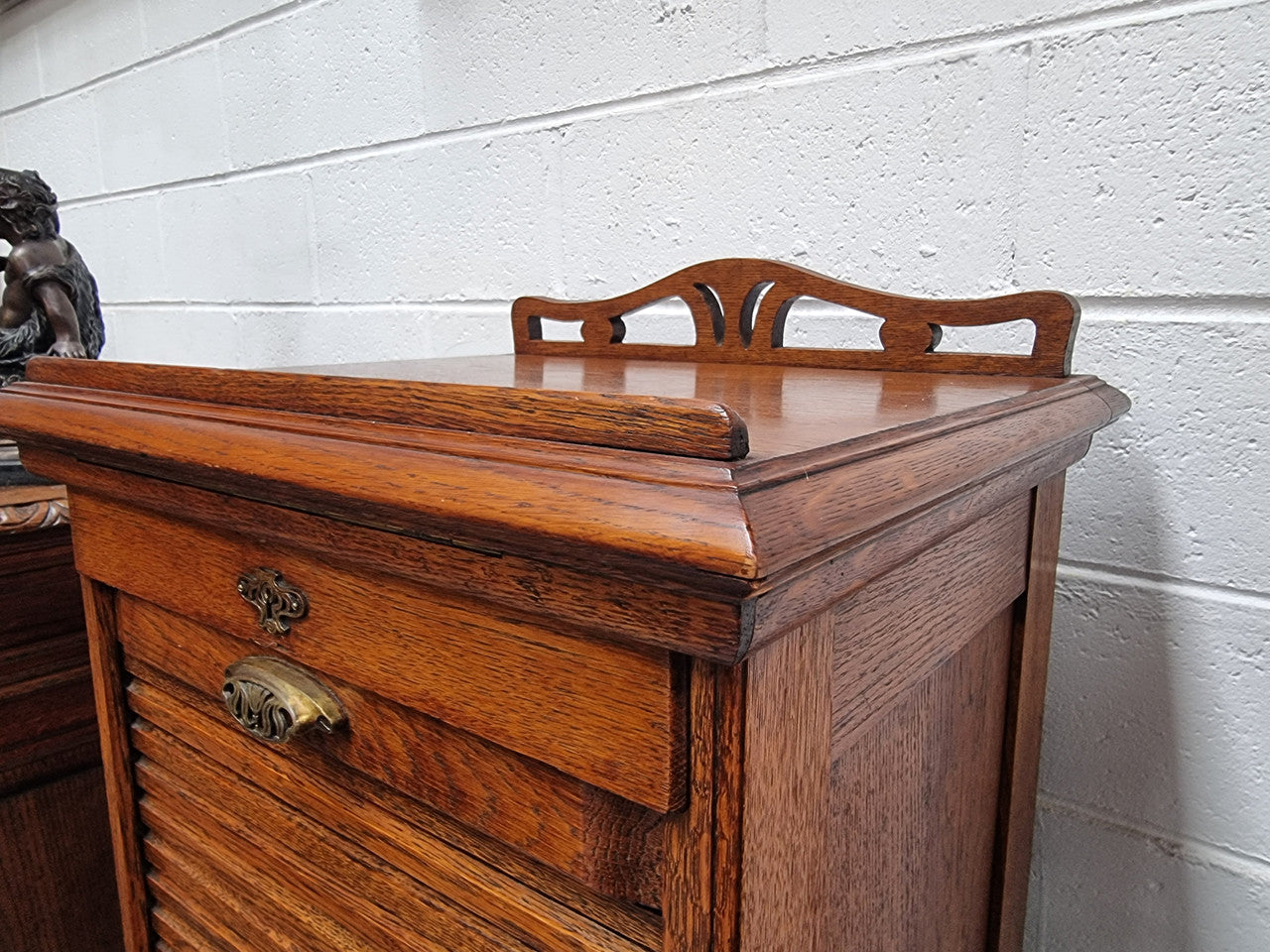 Antique Edwardian roll top Tambour file cabinet desk. This practical antique tambour front filing cabinet dates around 1900 in the Edwardian period and is constructed from Oak. This antique cabinet has an adjustable writing slope, above a tambour front with key and working lock. It has been sourced locally and is in good original detailed condition.