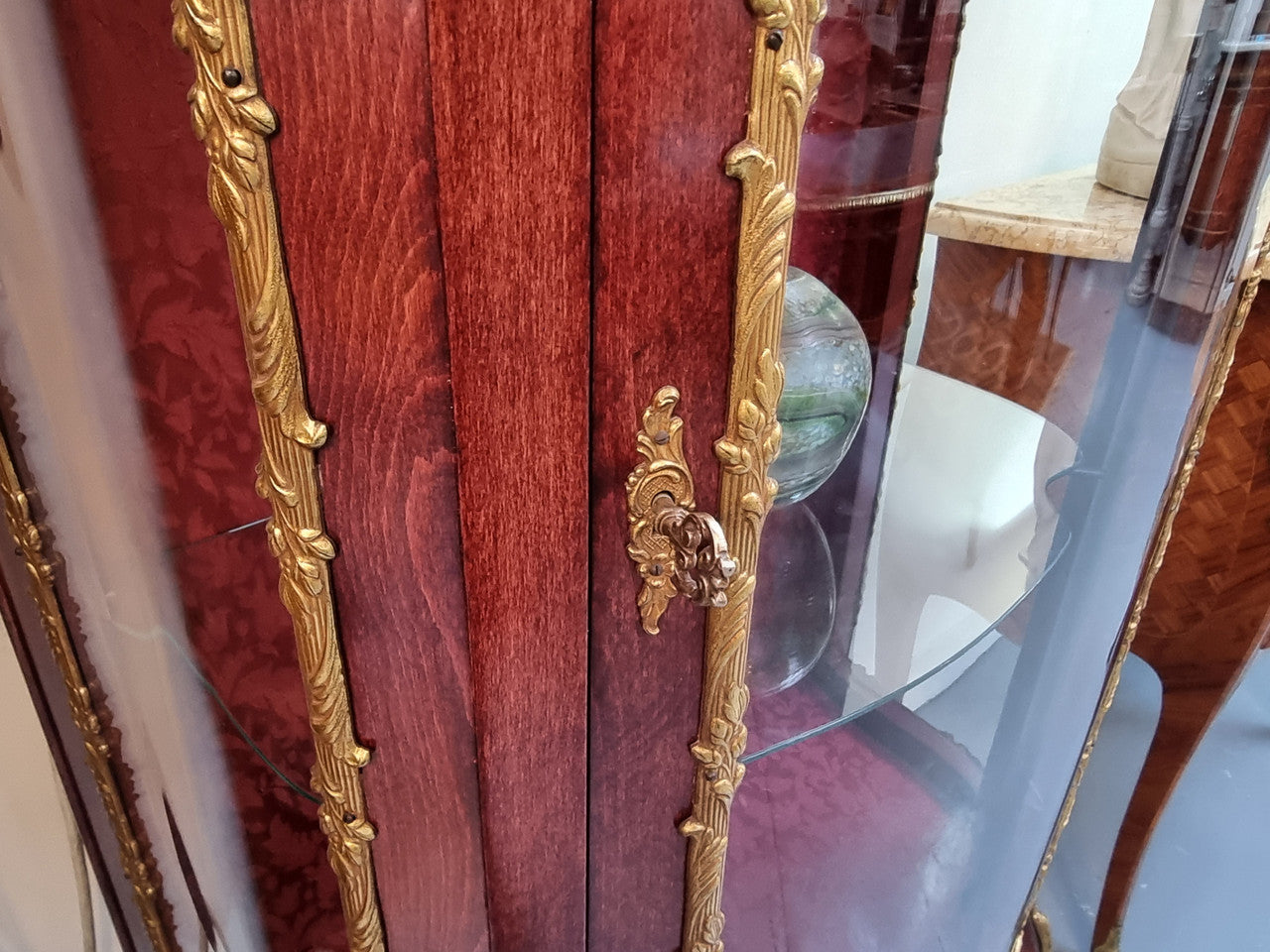 French Mahogany two shelf vitrine with curved glass and brass mounts. It has a lovely frabic interior and two glass shelves. In good original detailed condition.