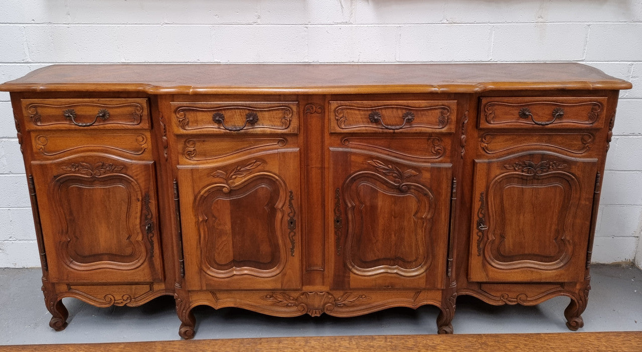 A Beautifully carved French Walnut Louis XV style four door sideboard. Plenty of storage space with four doors as well as four drawers. It is in good original detailed condition.