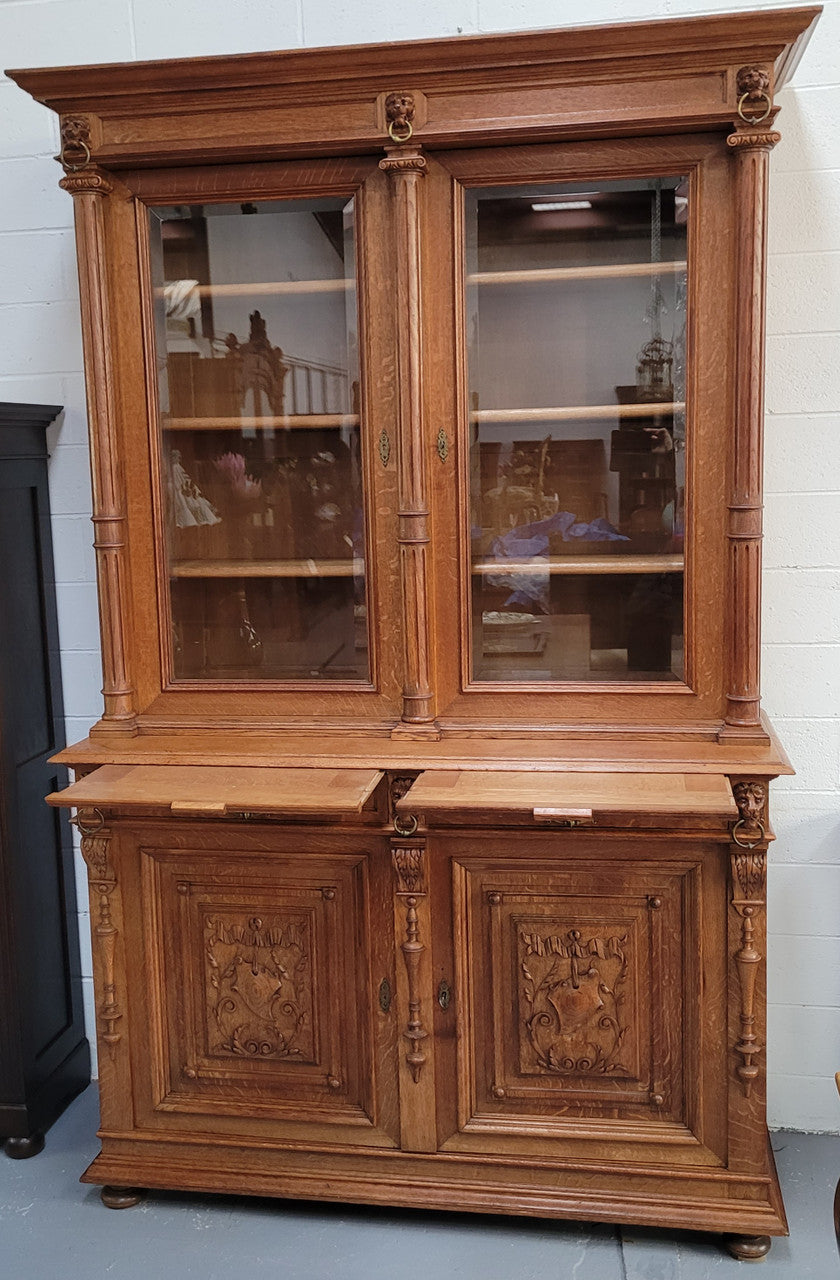 Amazing French 19th Century Oak two-door bookcase. Amazing detailed carvings throughout and plenty of storage space with three adjustable shelves at the top, two drawers, and a further shelf at the bottom. Also has two pull out reading slides giving you a large area to view your books on. In very good original detailed condition.