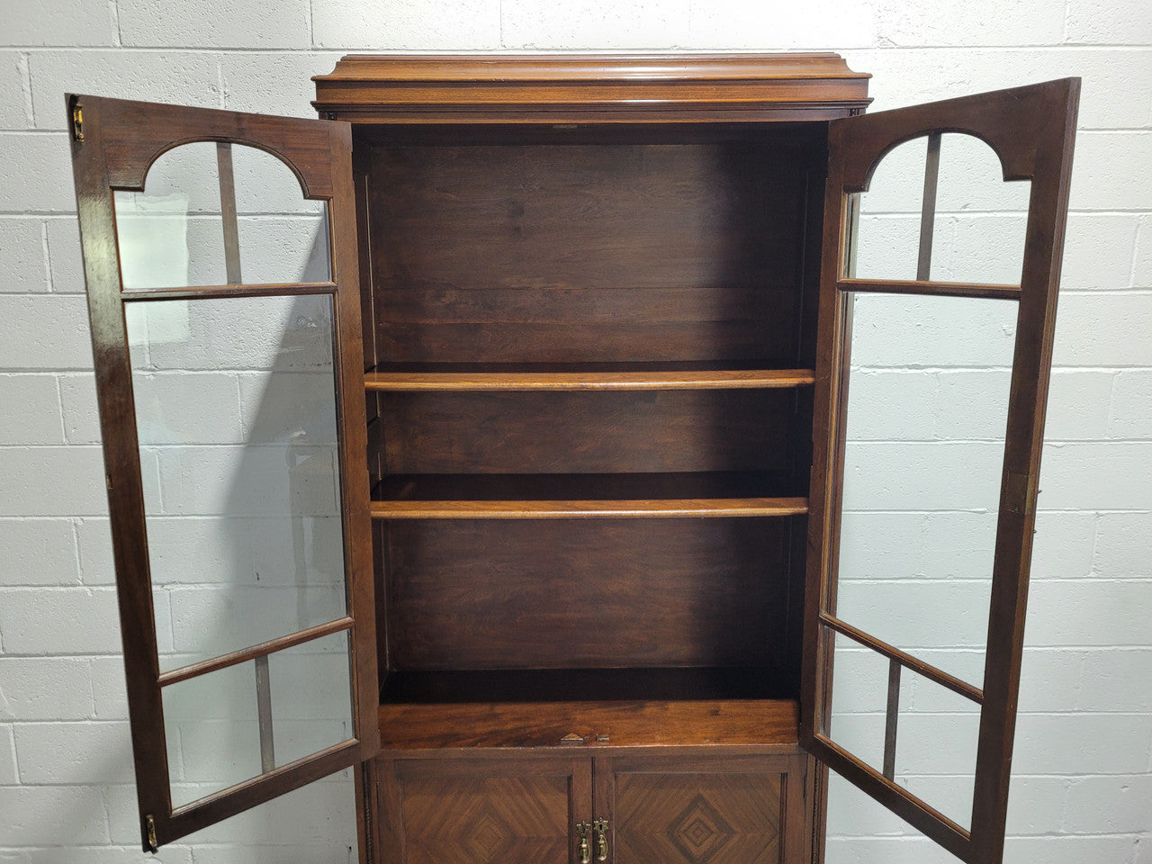 English Walnut two door bookcase with original glass. It has three adjustable shelves and hidden storage below behind two smaller doors. It is in food original condition.