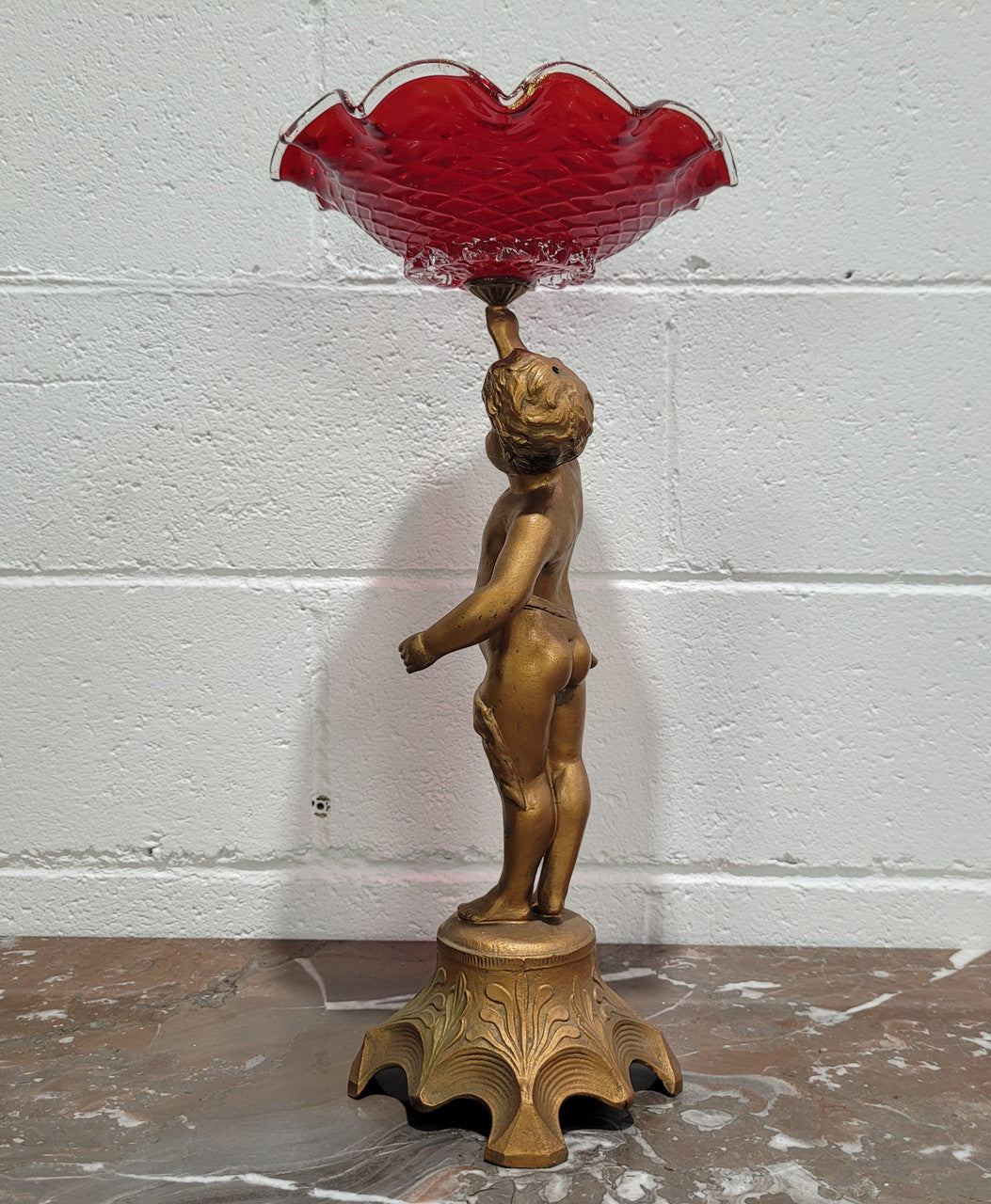 Late Victorian spelter table centerpiece/comfort featuring putti holding ruby glass bowl. In good original condition with no damage to the glass.