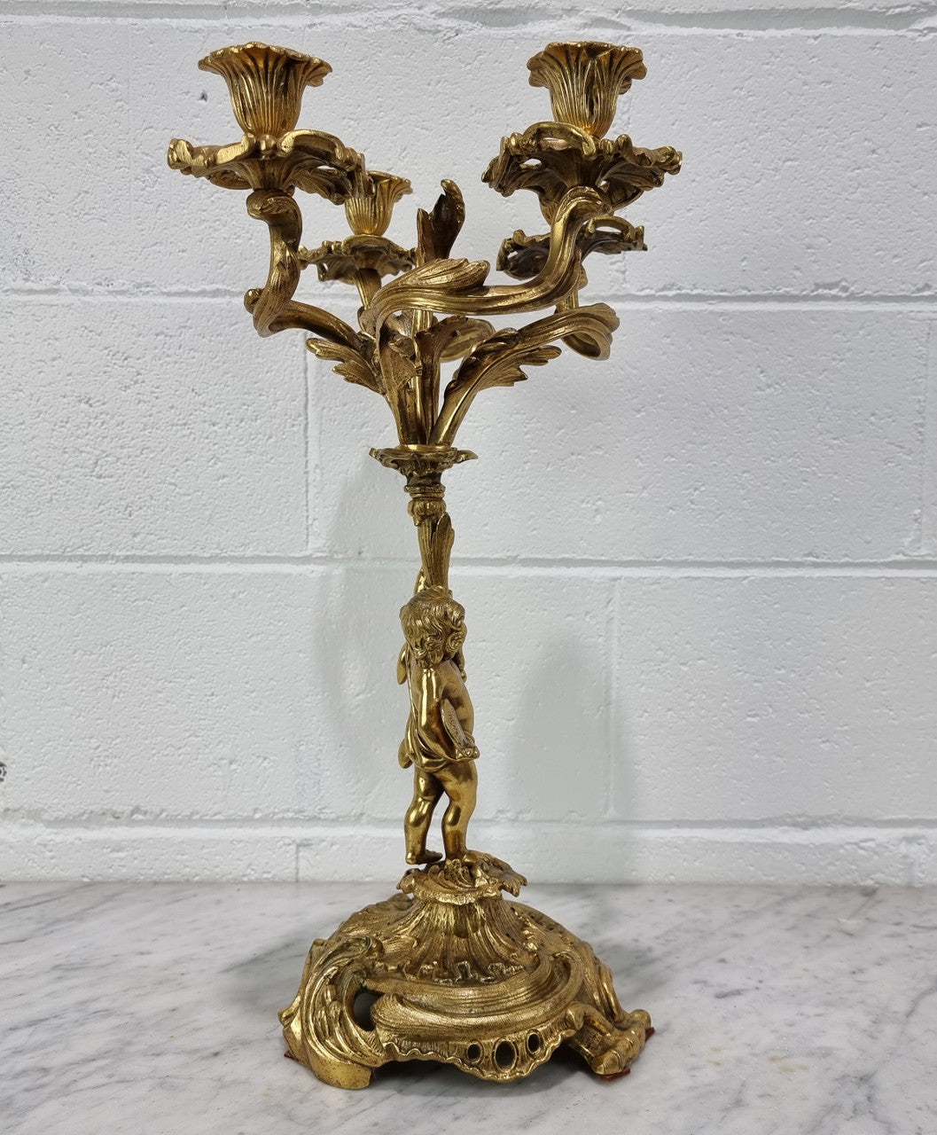 A pretty 19th Century French gilt bronze candelabra featuring a cherub. In good condition. Circa 1880.