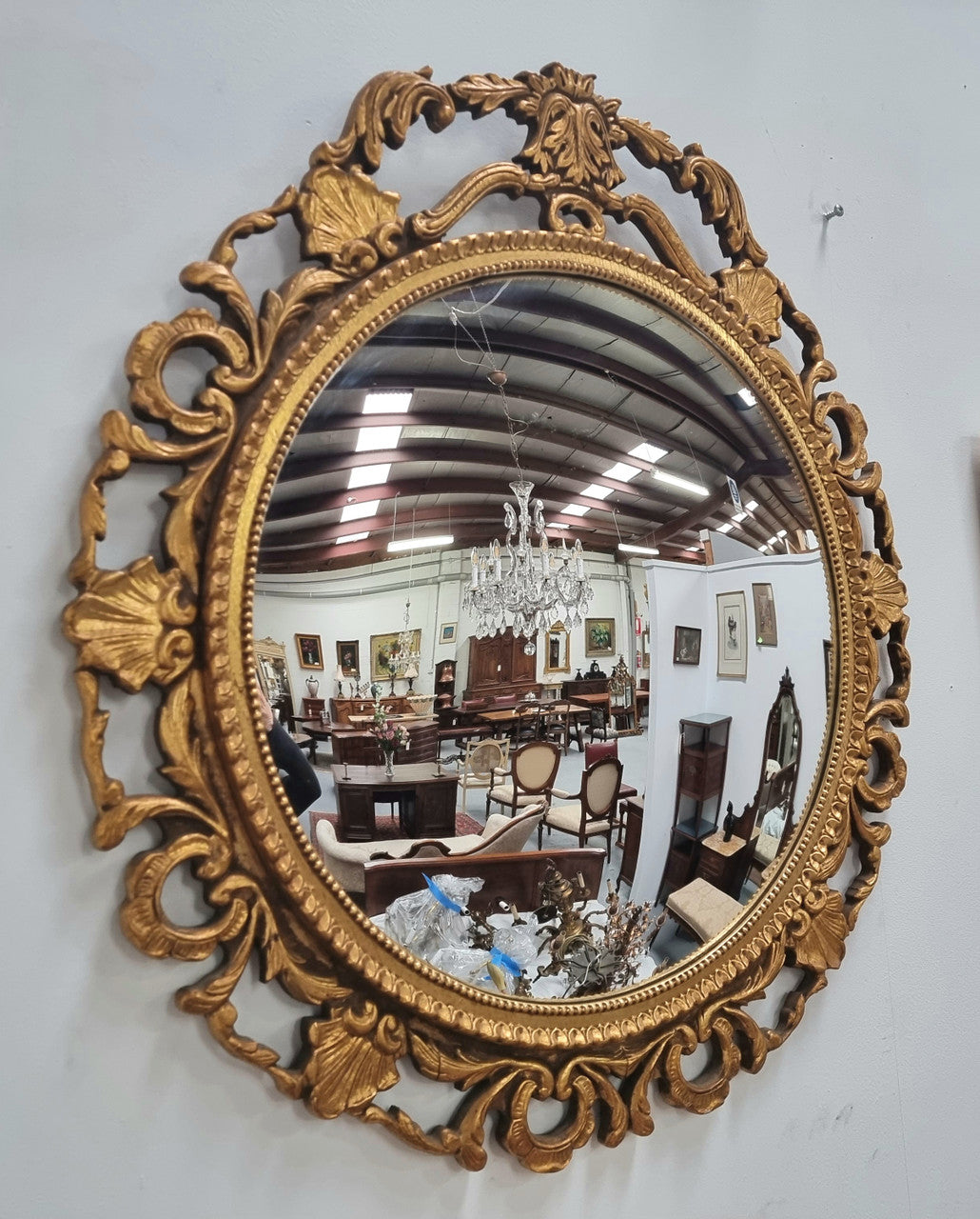 Large round convex mirror in a decorative carved wood gilt frame. In good original detailed condition.
