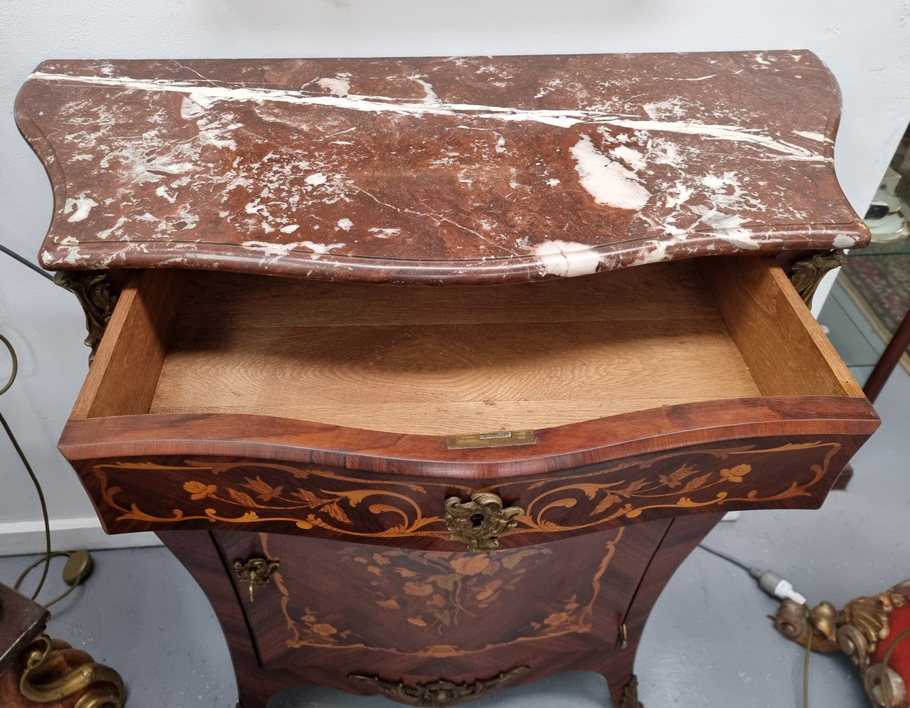 Stunning French Transitional style Mahogany marquetry inlay salon cabinet in the bombe shape. It has one draw, one shelf, marble top & ormolu decoration. Sourced from France and in good original detailed condition.
