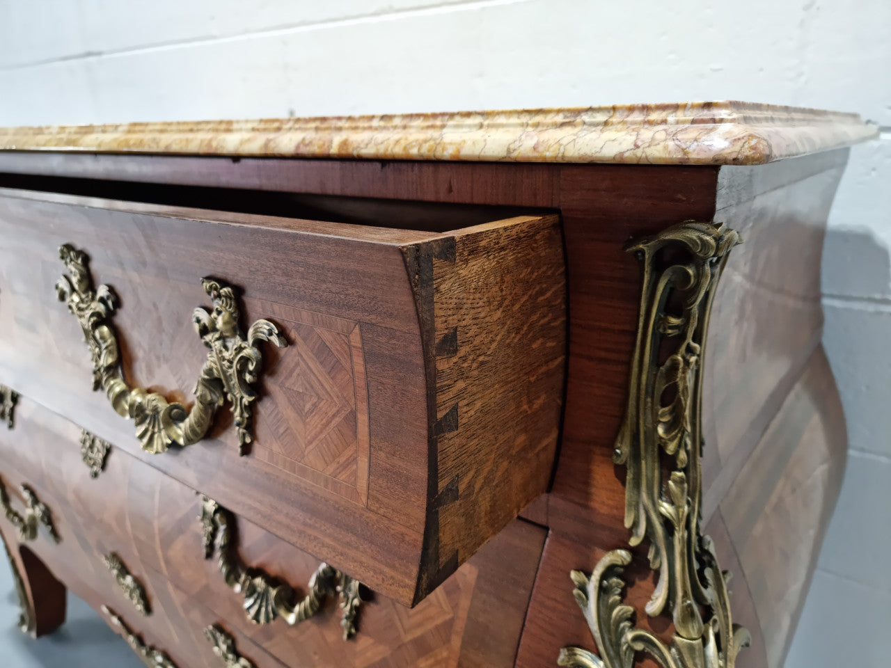 A beautifully inlaid parquetry three drawer commode with a lovely marble top, and decorative ormolu mounts. In good original detailed condition. Circa 1930