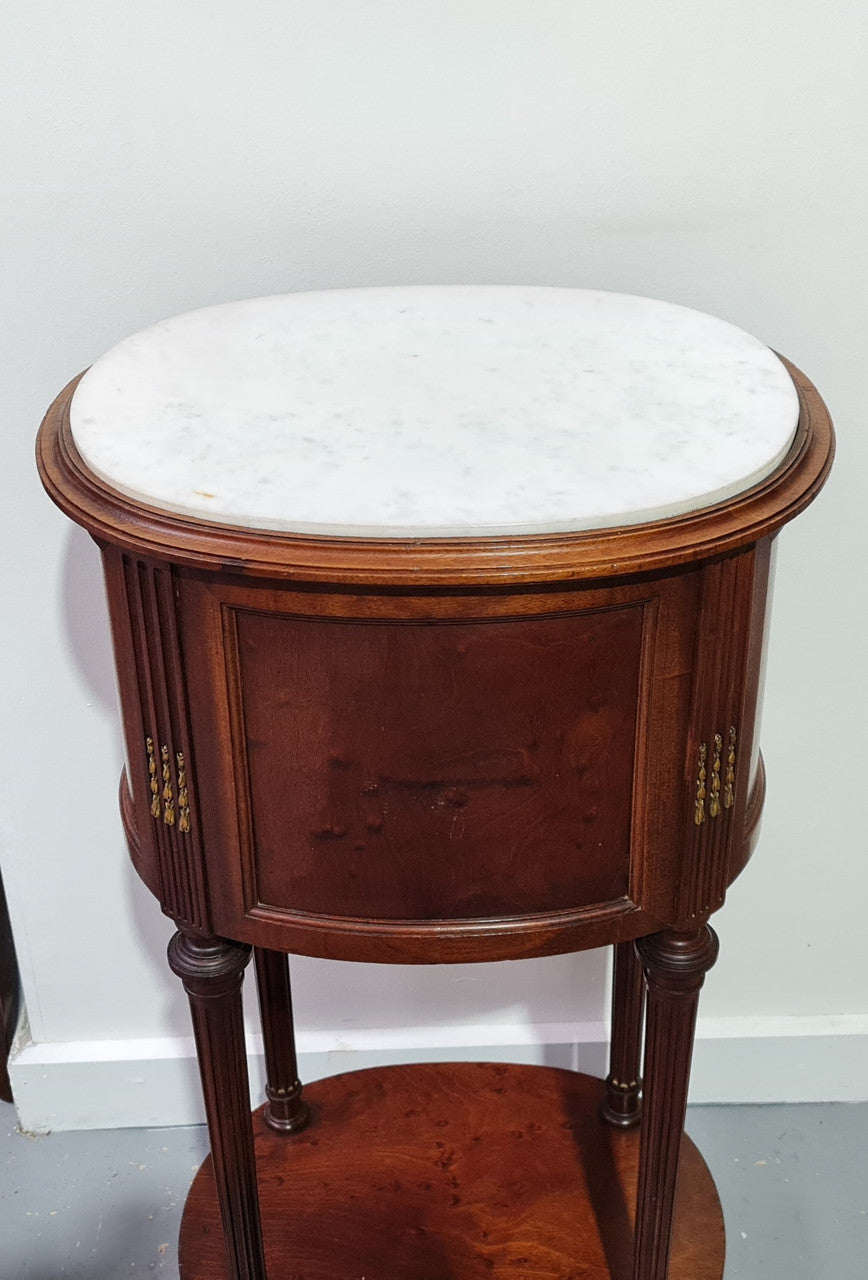 Round Louis XVI style Mahogany marble top side table. It has one drawer and a cupboard for storage. It is in good original detailed condition.
