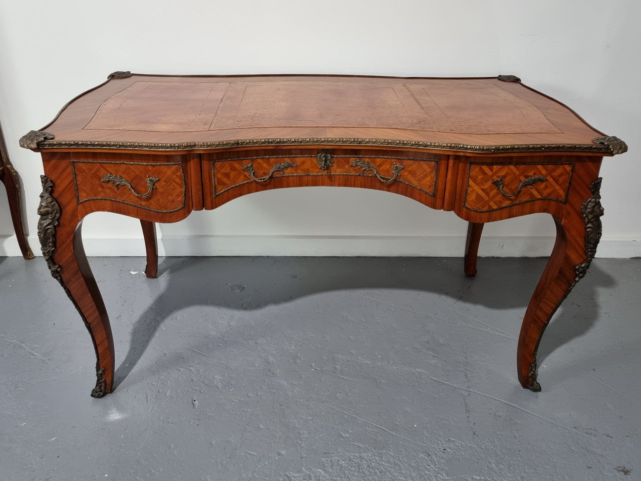 An impressive French kingwood and ormolu mounted bureau plat. It has a brown tooled leather writing surface, three decorated frieze drawers to the shaped apron with foliate swing handles and well cast figural mounts. Beautiful cabriole legs with decorative ormolu mounts and trims throughout. In good original detailed condition.