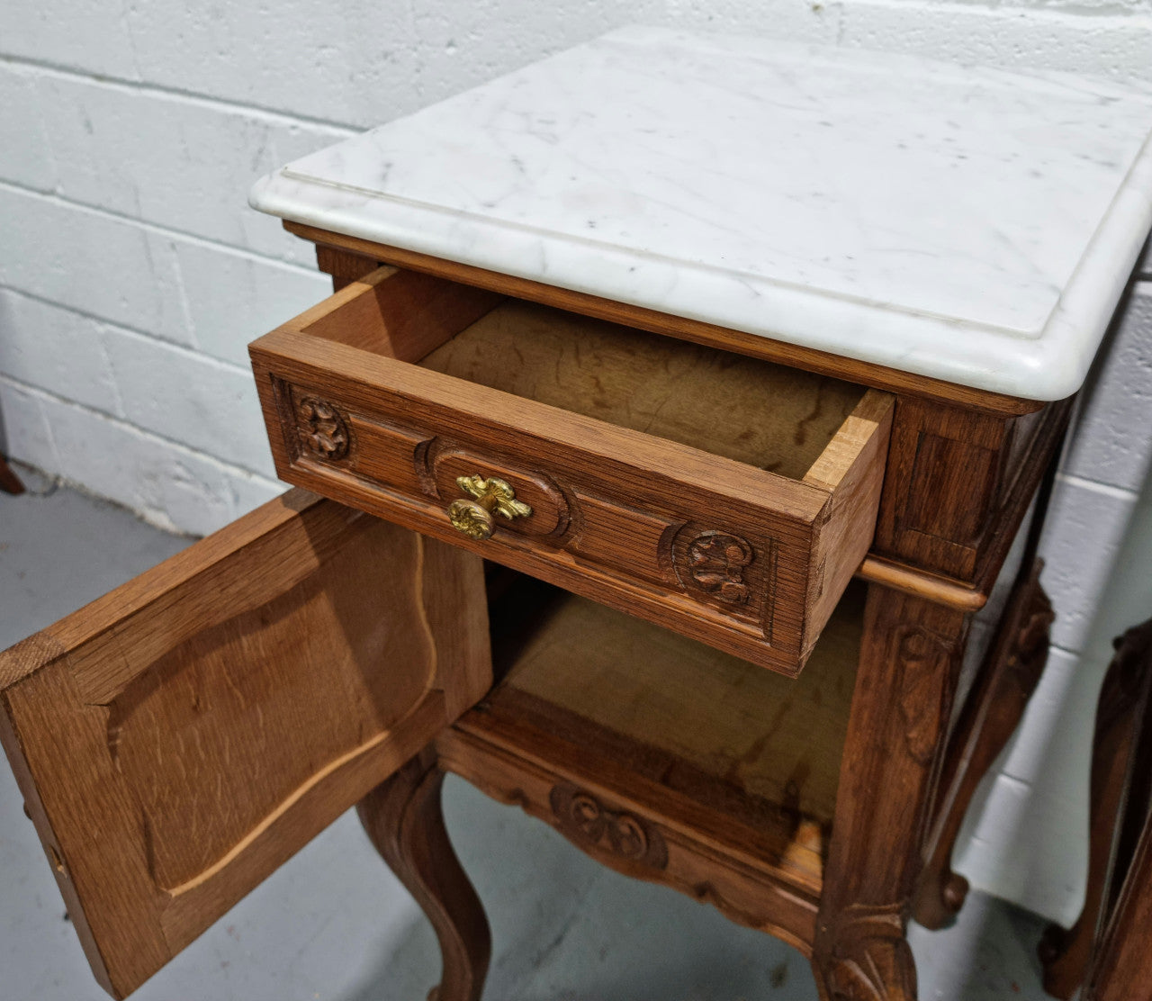 Lovely pair of French Oak carved Louis XV style bedside cabinets with a white marble top, drawer and cupboard in good original detailed condition.