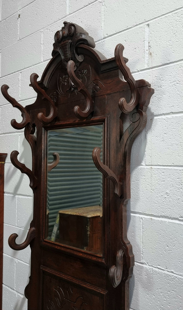 A beautiful Henry II style narrow French Oak hall stand. It has beautiful decorative carvings as well as 8 wooden hooks and storage for umbrellas and walking sticks. In good original detailed condition.
