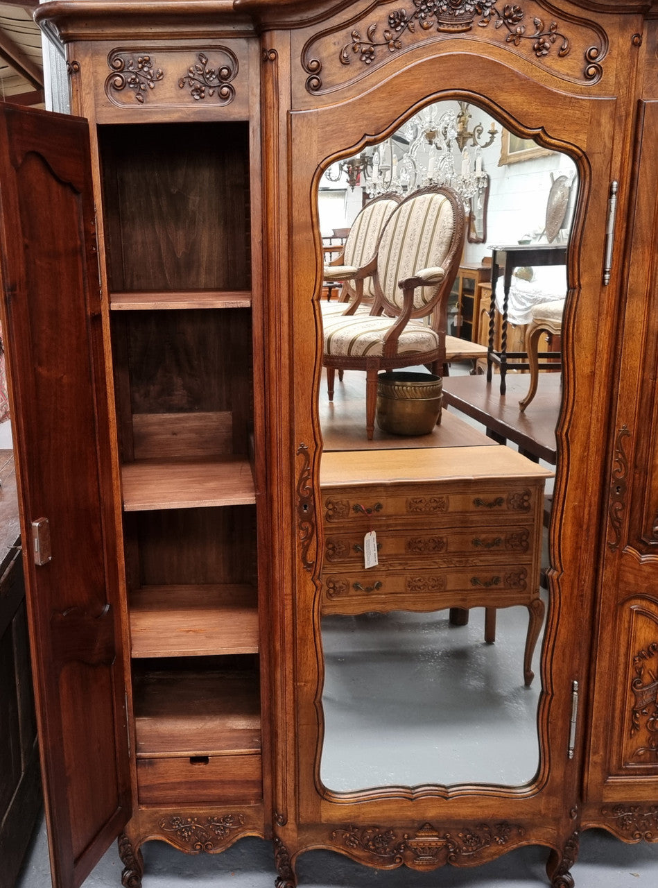 French Walnut Louis XV style three door armoire with 10 fully adjustable shelves in total spread over three sections, two drawers and a mirrored middle door. It has been sourced from France and in good original detailed condition.