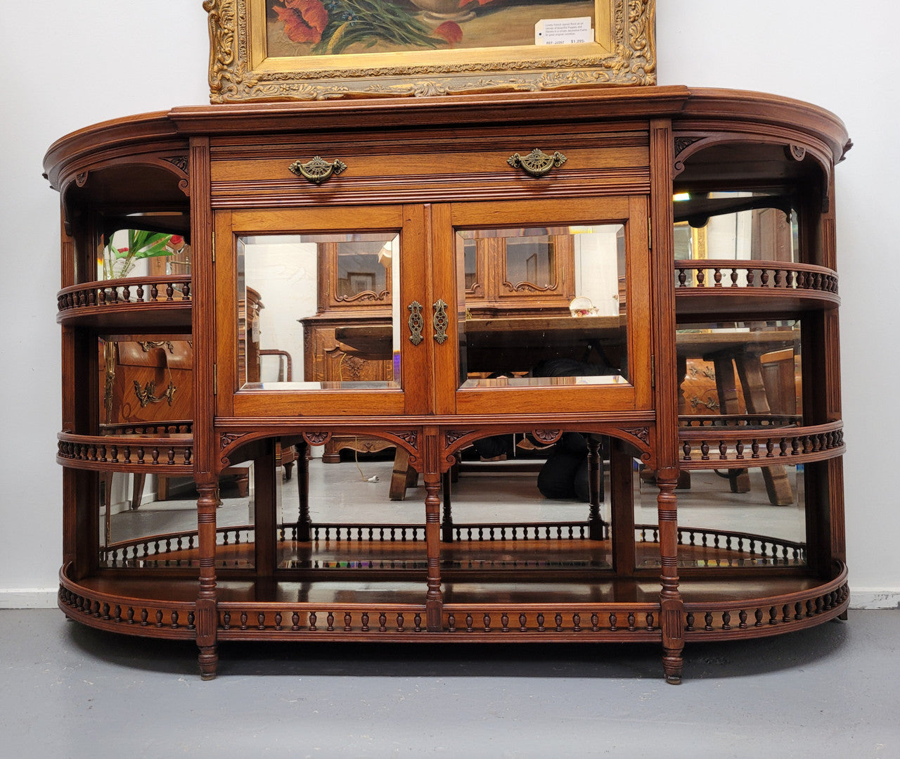 A high quality Antique Walnut sideboard featuring two mirrored doors, two drawers and five open shelf areas with mirror backing. It is in good original detailed condition.