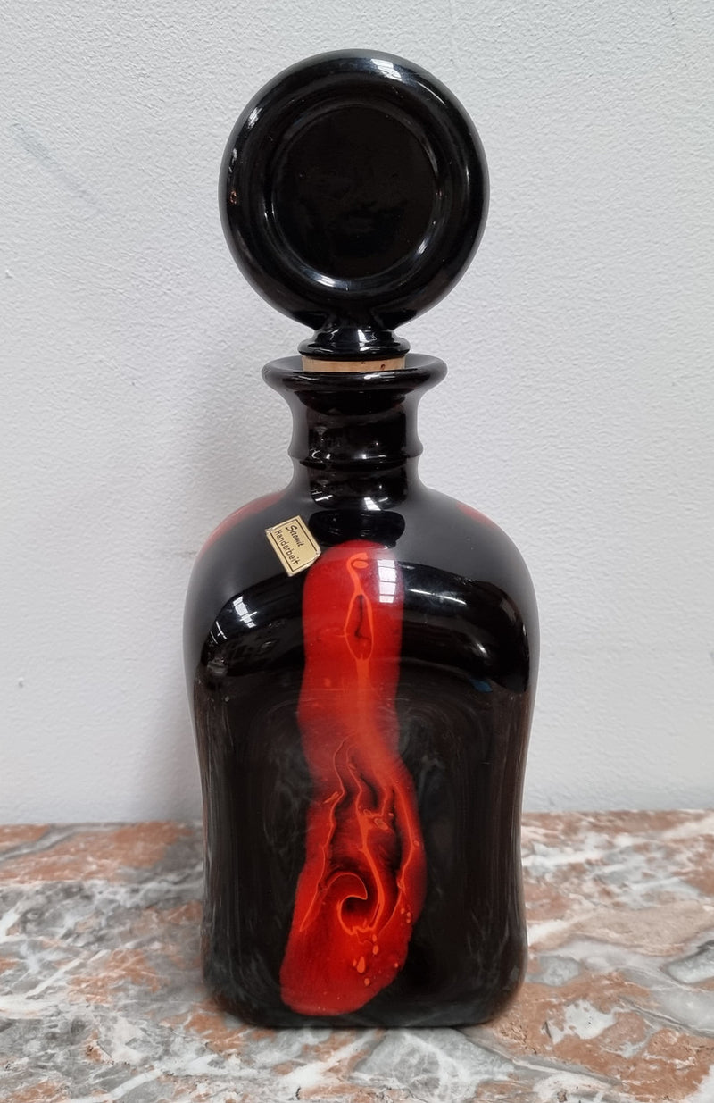 Vintage Designer glass carafe by “Stromit Handarbeit”.  Dark background with flashes of orange/red.