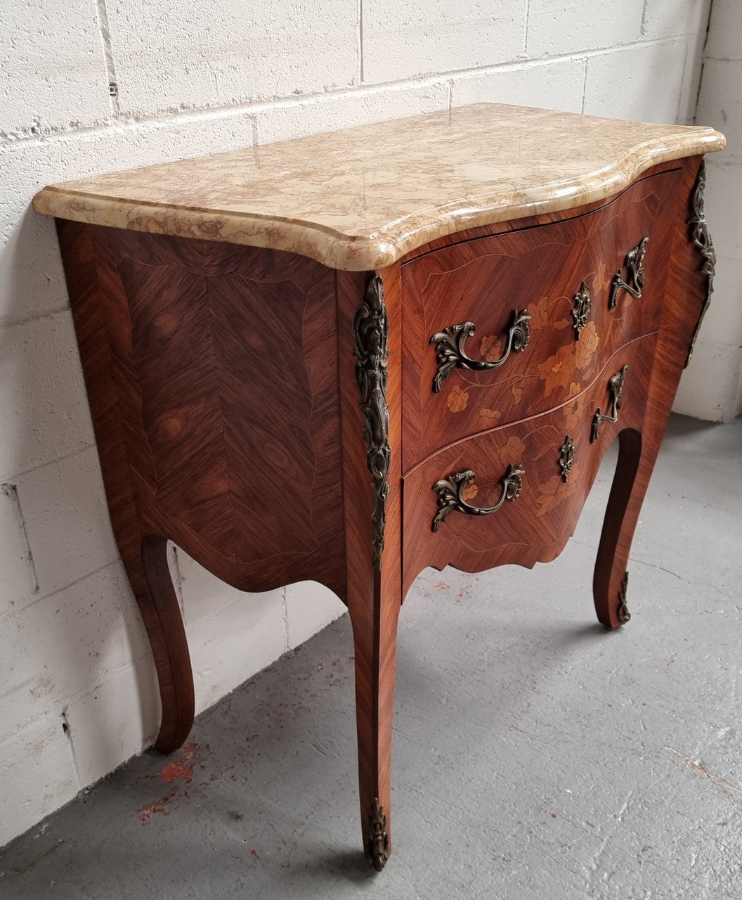 A timeless and compact French Louis XV style two drawer Kingwood marquetry inlaid commode. It features a stunning marble marble top and decorative mounts. The compact design of this commode ensures versatility, making it a perfect addition to any living space, bedroom or hallway. It has been sourced directly from France and is in good original detailed condition.
