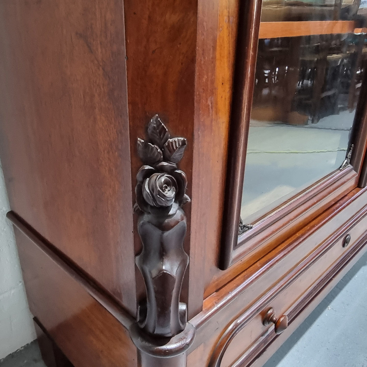 Antique Mahogany two door Biedermeier style bookcase with four fully adjustable shelves and a drawer at the bottom. The two wooden finials at the top are easily removed for a different look of desired. In good original detailed condition.