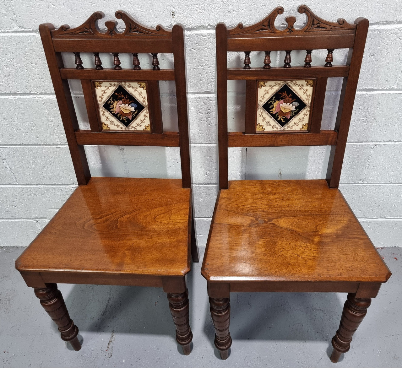 Pair of Edwardian Mahogany hall chairs with original tile in back. They are in very good original detailed condition.