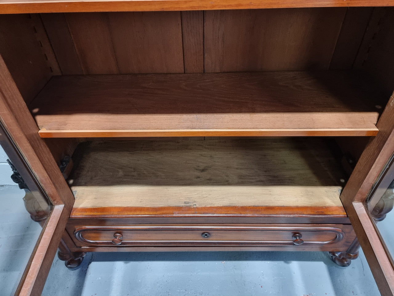 Antique Mahogany two door Biedermeier style bookcase with four fully adjustable shelves and a drawer at the bottom. The two wooden finials at the top are easily removed for a different look of desired. In good original detailed condition.