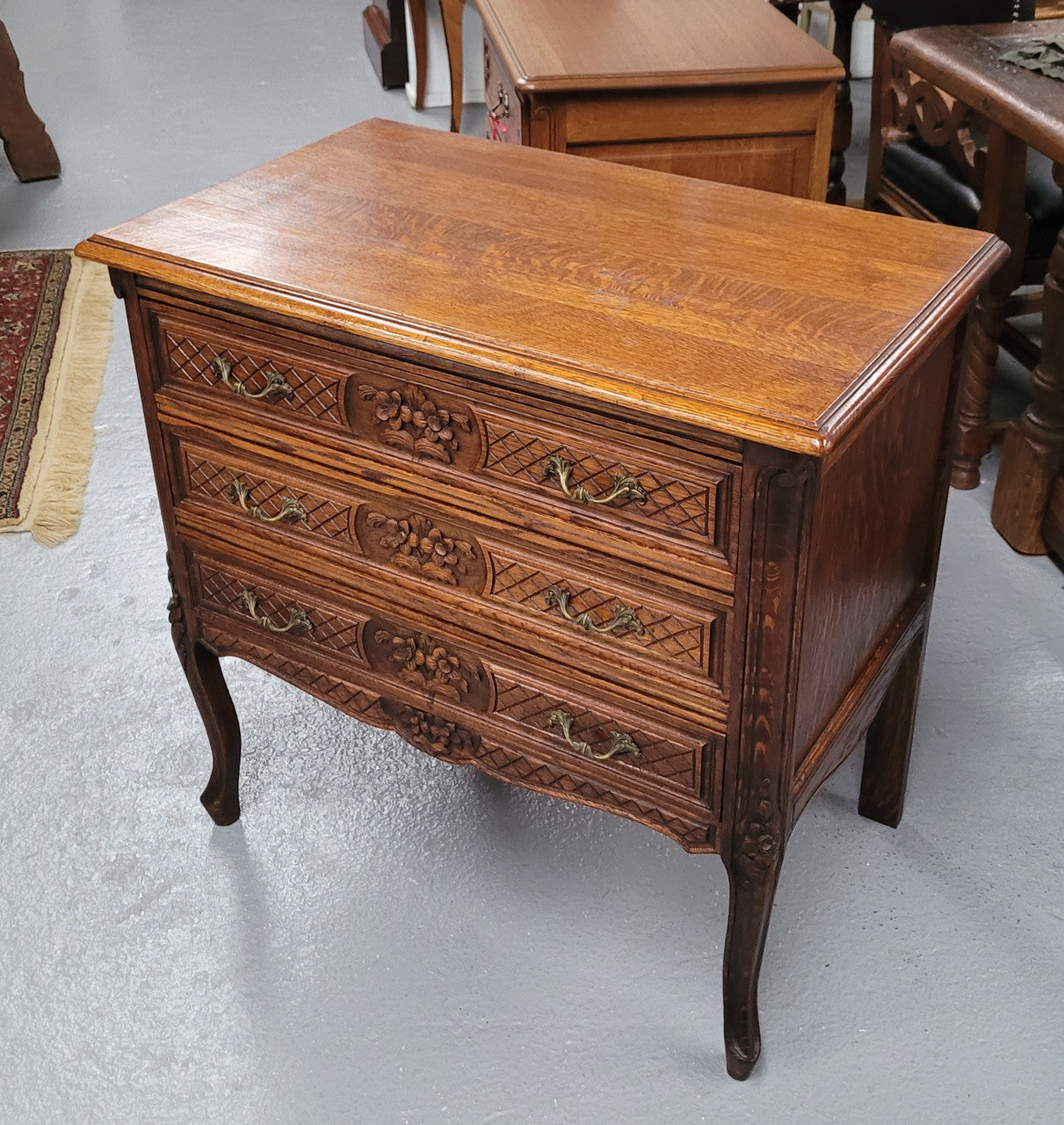 Rustic Louis XV style Oak petite three drawer chest featuring attractive carvings. It has been sourced locally and it is in good original detailed condition.