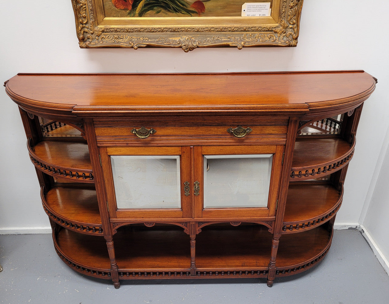 A high quality Antique Walnut sideboard featuring two mirrored doors, two drawers and five open shelf areas with mirror backing. It is in good original detailed condition.