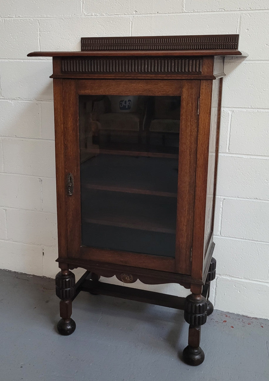 A very practical compact Oak Tudor style display cabinet with three fixed shelves. In good original detailed condition.