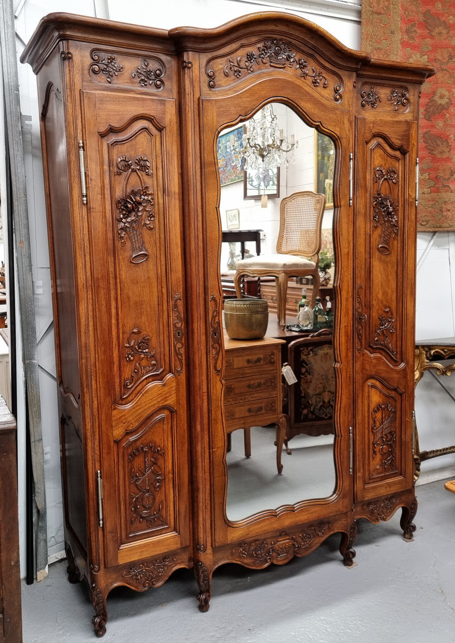 French Walnut Louis XV style three door armoire with 10 fully adjustable shelves in total spread over three sections, two drawers and a mirrored middle door. It has been sourced from France and in good original detailed condition.