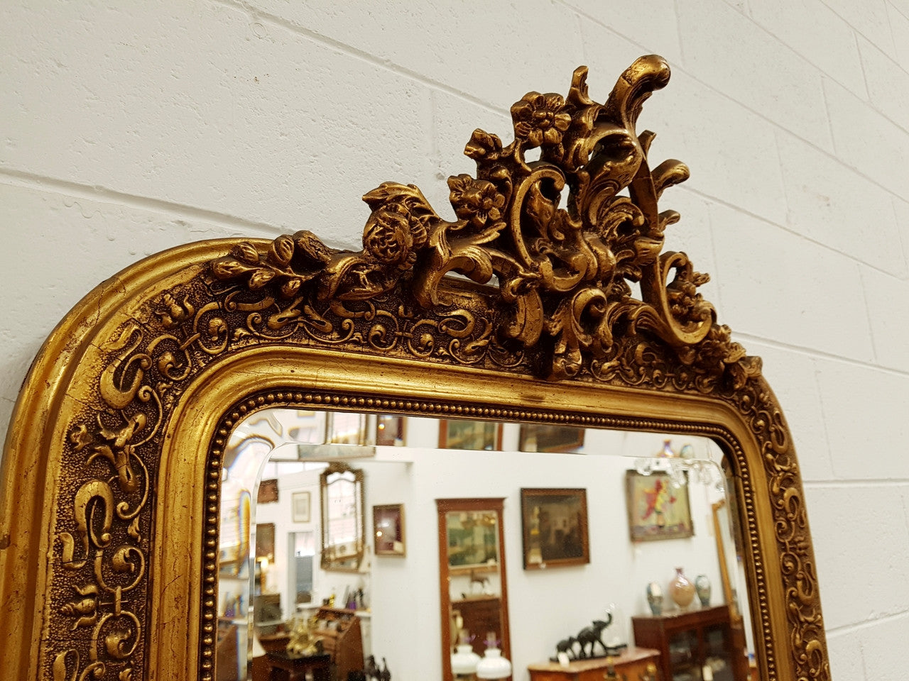 19th Century French Louis XV style gilt wall mirror with fabulous highly decorative crest at the top and a beveled edge mirror. In good original detailed condition.