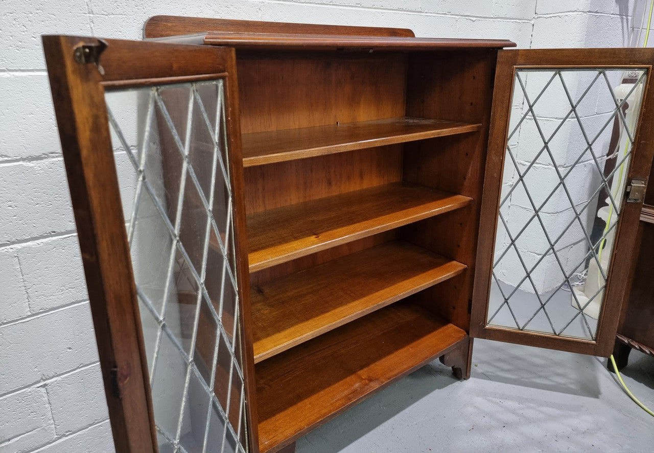 Lovely leadlight two door Oak bookcase/display cabinet with four wooden shelves. It is in good original detailed condition.