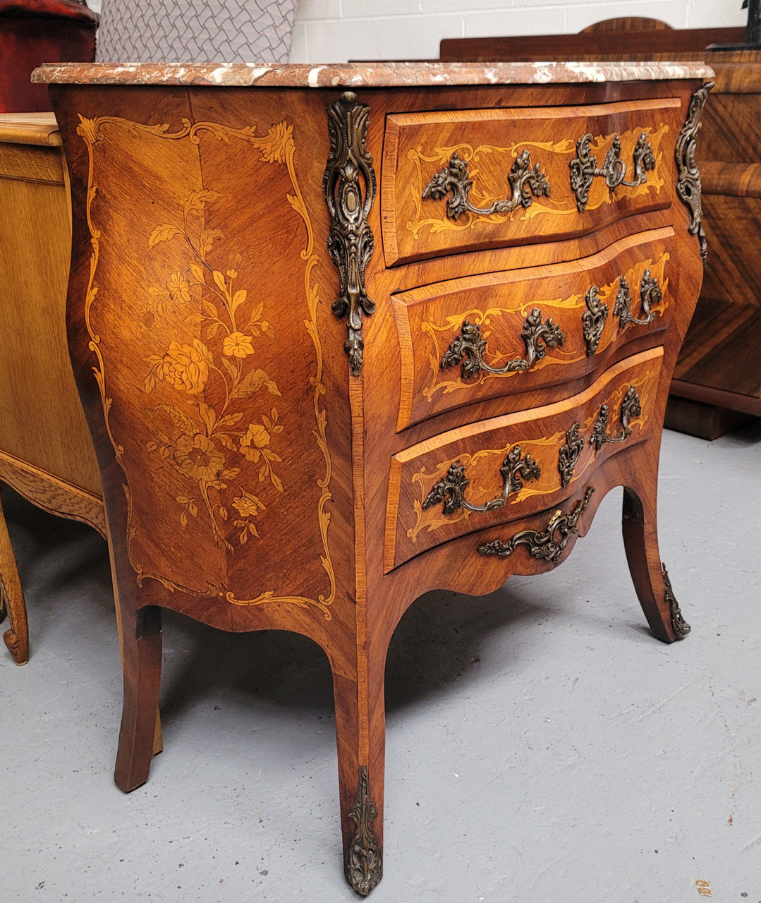 Antique French Louis XV style compact three drawer marble top commode with marquetry inlay and ormolu mounts. Sourced from France and in good original detailed condition.