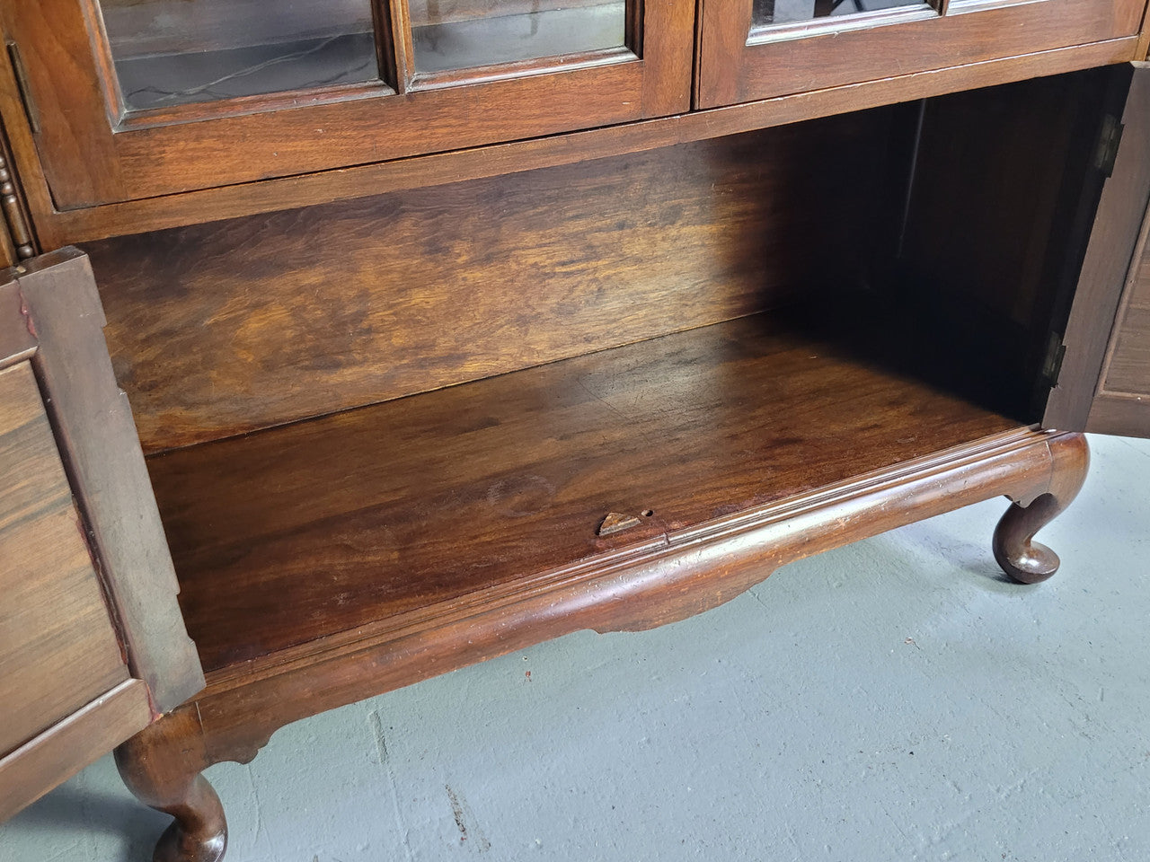 English Walnut two door bookcase with original glass. It has three adjustable shelves and hidden storage below behind two smaller doors. It is in food original condition.