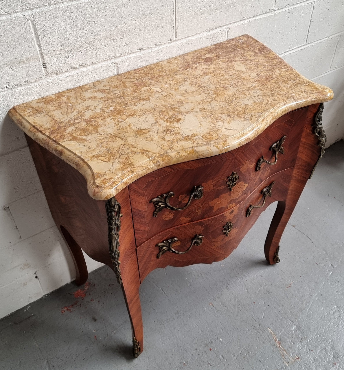 A timeless and compact French Louis XV style two drawer Kingwood marquetry inlaid commode. It features a stunning marble marble top and decorative mounts. The compact design of this commode ensures versatility, making it a perfect addition to any living space, bedroom or hallway. It has been sourced directly from France and is in good original detailed condition.