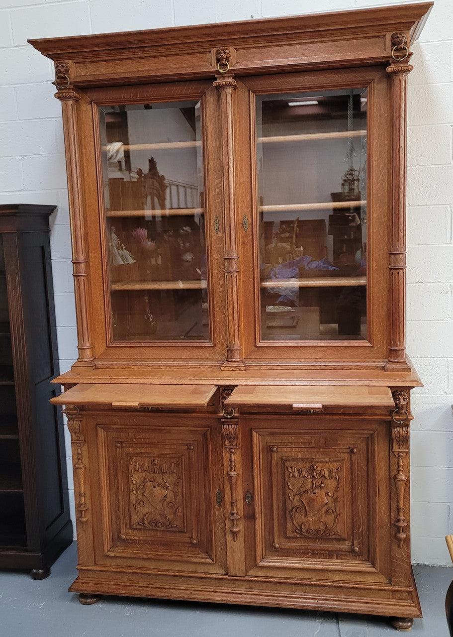 Amazing French 19th Century Oak two-door bookcase. Amazing detailed carvings throughout and plenty of storage space with three adjustable shelves at the top, two drawers, and a further shelf at the bottom. Also has two pull out reading slides giving you a large area to view your books on. In very good original detailed condition.