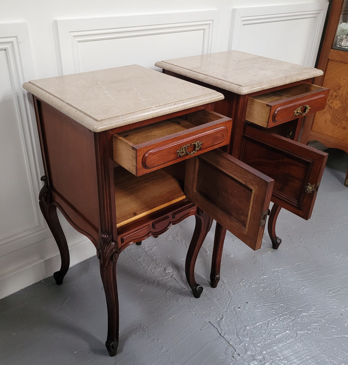 Pair of French Antiloopque Louis XV style Walnut and marble top bedsides. They have lovely carvings along with a drawer and cupboard space. They are in good original detailed condition and have been sourced from France