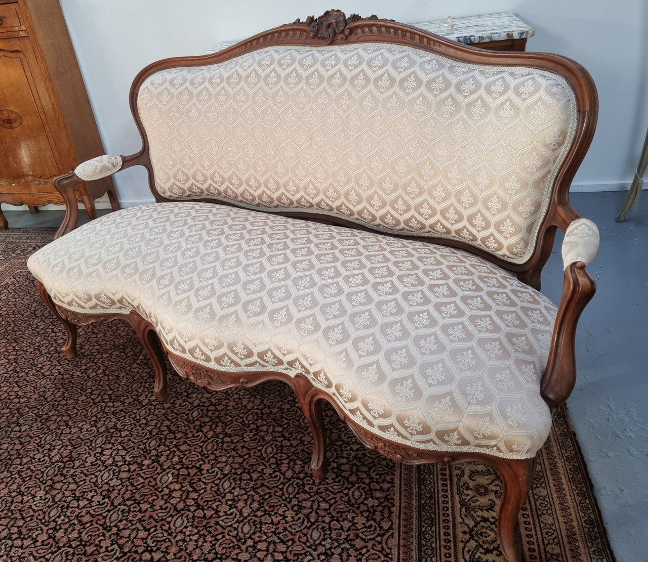 A late 19th Century French Walnut Louis XV style settee with a serpentine front. This settee upholstery is like new and is in very good condition.