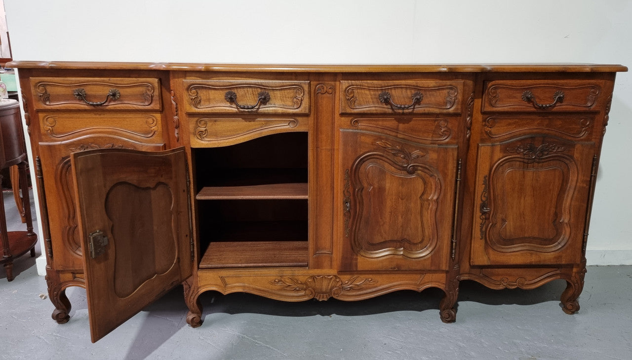 A Beautifully carved French Walnut Louis XV style four door sideboard. Plenty of storage space with four doors as well as four drawers. It is in good original detailed condition.
