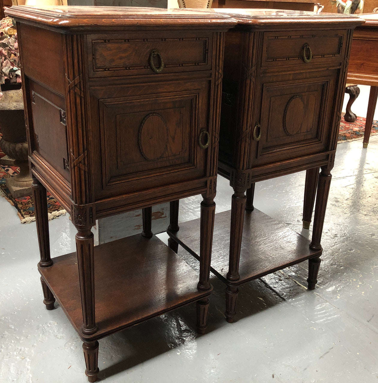 Lovely pair of French Oak Louis XVI style bedside cabinets with inset marble tops a drawer and a cupboard for storage. In good original detailed condition.