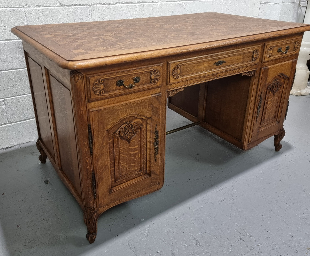 Fabulous French oak carved partners desk with a lovely parquetry top. It has three drawers and two cupboards on one side and two cupboards on the other side with no functioning drawers. It is in good original detailed condition.